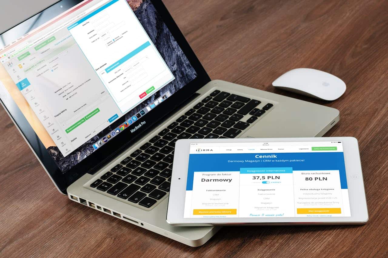 Laptop con software gestionale e tablet con listino prezzi di un servizio CRM e contabilità, strumenti digitali per e-commerce.